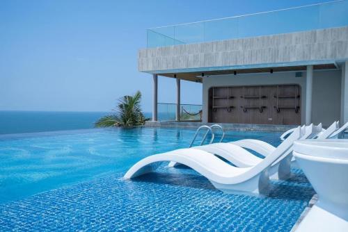 a swimming pool with white chairs and a swimming pool at APEC MANDALA Condotel in Phan Thiet