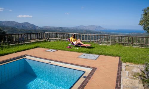 a woman sitting in a chair next to a swimming pool at Malathiros Traditional Villas in Maláthiros
