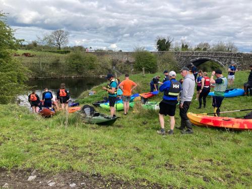 a group of people standing on the grass next to a river at Inny River Lodge in Rathowen