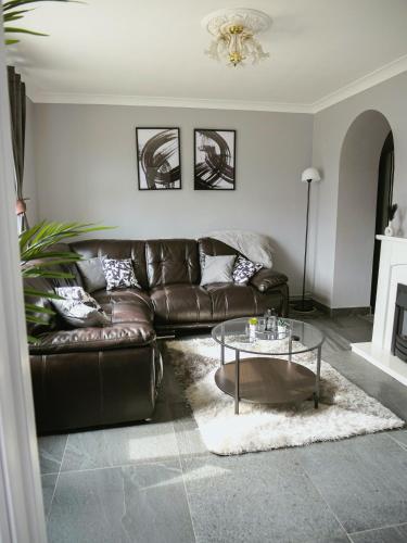 a living room with a leather couch and a glass table at Urban Oasis in Abbey Wood