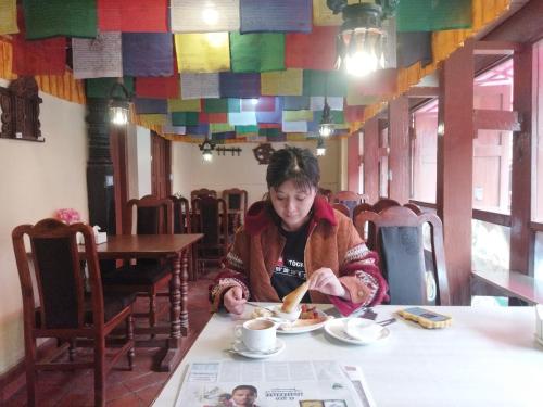 kobieta siedząca przy stole jedząca jedzenie w obiekcie HOTEL RUPAKOT AND ROOFTOP RESTAURANT w mieście Bhaktapur