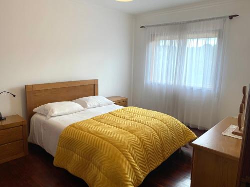 een slaapkamer met een bed met een gele deken en een raam bij ACONCHEGO HOME in Caldas de São Jorge