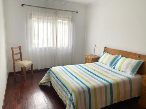 een slaapkamer met een bed, een stoel en een raam bij ACONCHEGO HOME in Caldas de São Jorge