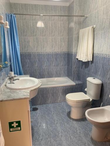 een badkamer met een toilet, een wastafel en een bad bij ACONCHEGO HOME in Caldas de São Jorge