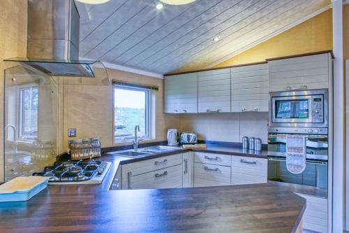 a kitchen with white cabinets and a stove top oven at Newlands Holidays in Bridport