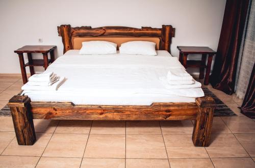 a wooden bed with white sheets and pillows on it at Fortetsya in Umanʼ