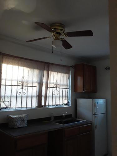 a kitchen with a ceiling fan and two windows at Errol and Nancy Place in Nassau