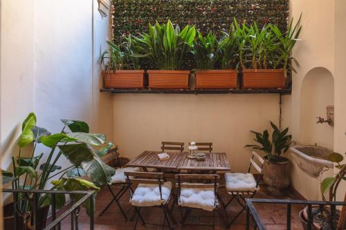 einen Tisch und Stühle in einem Zimmer mit Pflanzen in der Unterkunft Maison Barchetta in Via Giulia - Piazza Navona in Rom