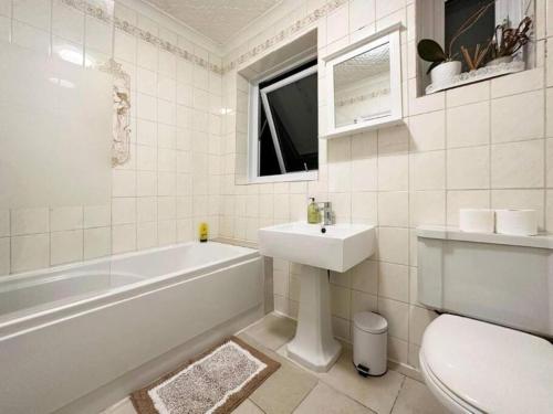 a bathroom with a tub and a sink and a toilet at Charming 3-bedroom family home in London