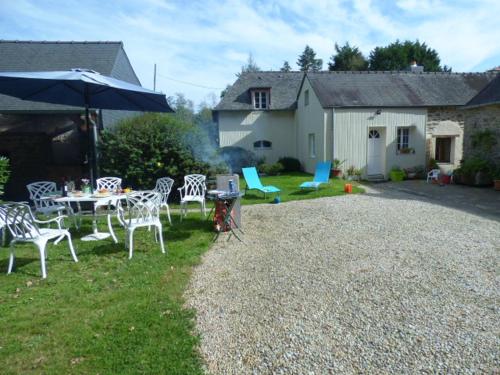 - une cour avec une table, des chaises et un parasol dans l'établissement Château de BEL AIR, à Aucaleuc