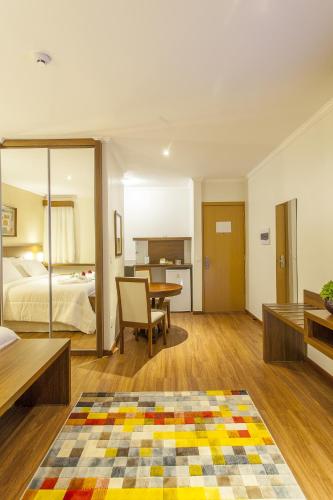 a bedroom with a bed and a table in a room at São Carlos Marklin Suítes in São Carlos