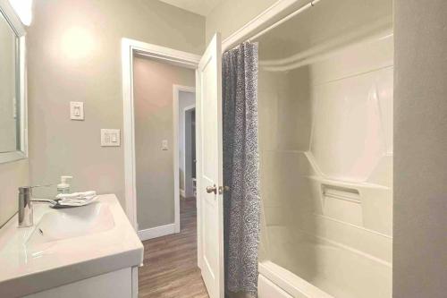 La salle de bains blanche est pourvue d'un lavabo et d'une douche. dans l'établissement White House Suite - Sleeps 4, à Saint Catharines