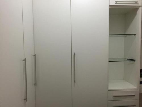 a white closet with white doors and shelves at Quarto no posto 5 de Copacabana in Rio de Janeiro