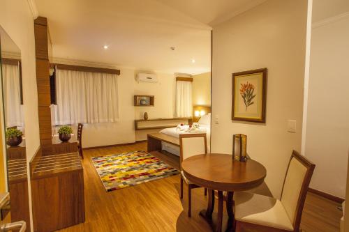 a living room with a table and a bed at São Carlos Marklin Suítes in São Carlos