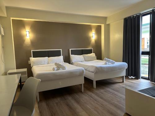Habitación de hotel con 2 camas y ventana en D'ELEMENTS HOTEL AND DORMITORY en Laoag