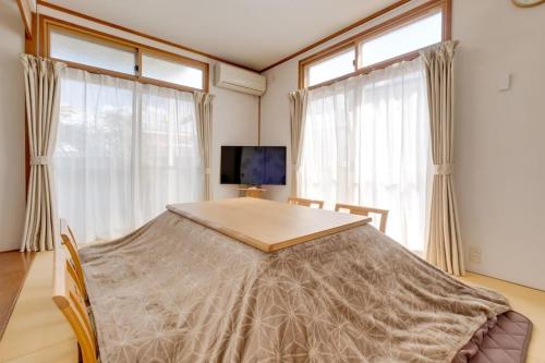 um quarto com uma mesa e duas janelas e uma televisão em Forest Agata em Matsumoto