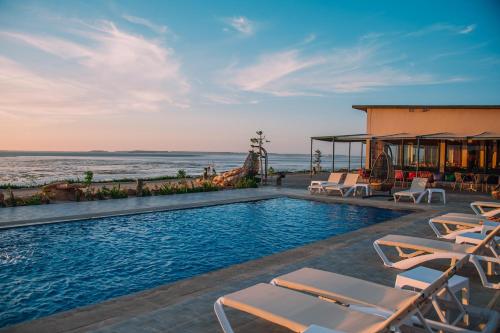 a swimming pool with chairs and the ocean in the background at PARAISO DAKHLA in Dakhla