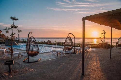 a resort with a pool with chairs and the ocean at PARAISO DAKHLA in Dakhla