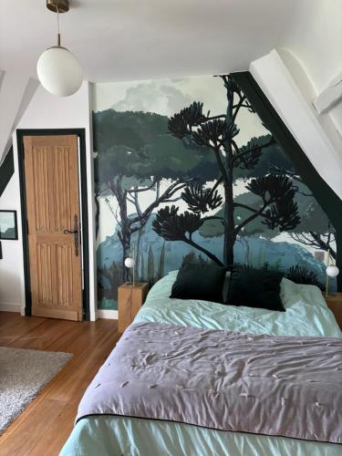 sypialnia z łóżkiem z malowidłem drzewnym na ścianie w obiekcie Maison de charme, près des plages du Débarquement w mieście Bayeux