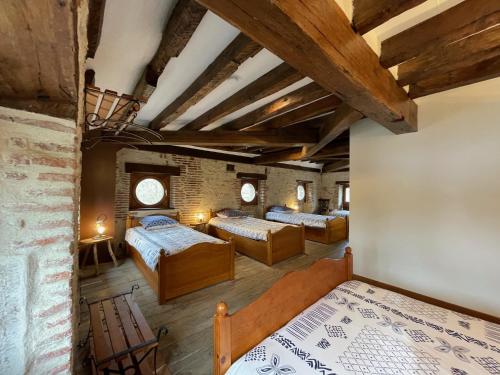 1 dormitorio con 4 camas y pared de ladrillo en Le relais de Mantelot, en Châtillon-sur-Loire