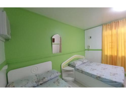 een groene kamer met 2 bedden en een raam bij OYO 1048 Jomckayl Apartelle in Naga