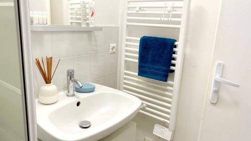 a white bathroom with a sink and a blue towel at Studio Cosy au pied de la gare de Cergy le Haut - 35 min de Paris in Cergy