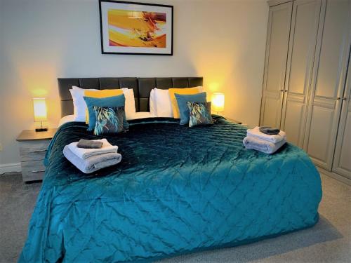 a bedroom with a large blue bed with towels on it at The Croft, North Staffordshire in Blythebridge