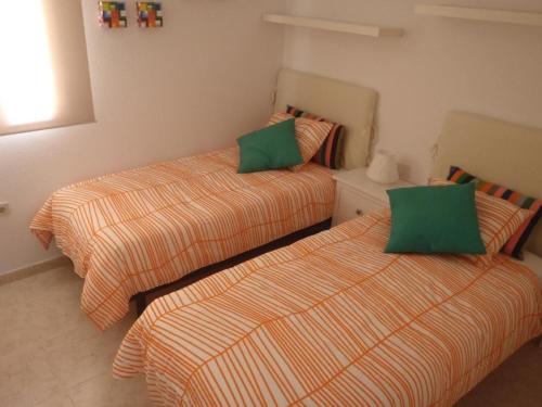 1 dormitorio con 2 camas y almohadas verdes en Komfortable Ferienwohnung in Morro Jable mit Großer Terrasse und Neben dem Strand en Morro del Jable