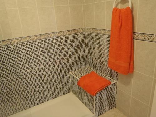 y baño con ducha y toalla de color naranja. en Komfortable Ferienwohnung in Morro Jable mit Großer Terrasse und Neben dem Strand en Morro del Jable