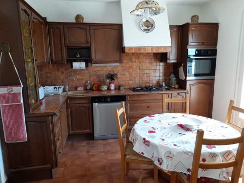 uma cozinha com armários de madeira e uma mesa com uma toalha de mesa em Maison de Lili em Florensac