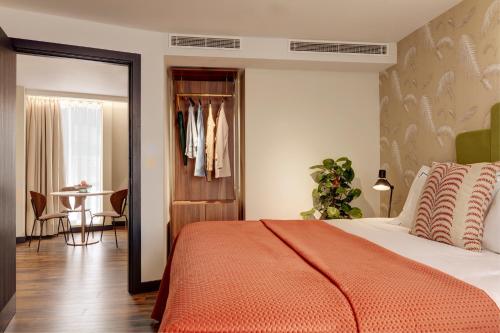 a bedroom with a bed with an orange blanket and a table at Brama in Bromley
