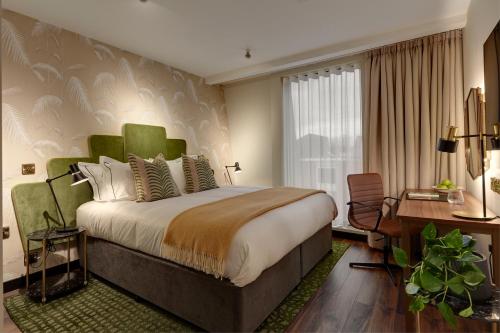 ein Hotelzimmer mit einem großen Bett und einem Schreibtisch in der Unterkunft Brama in Bromley