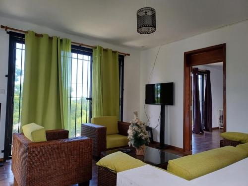 a living room with green curtains and chairs and a tv at Calodyne residence in Grand Gaube