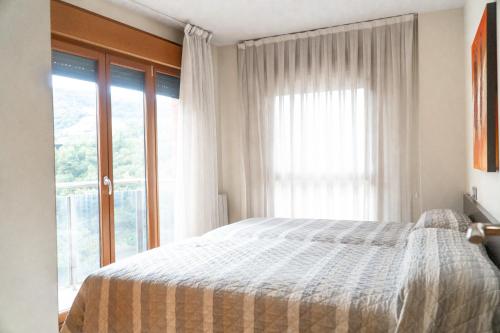a bedroom with a bed and a large window at Bilbao Apartamentos Atxuri in Bilbao