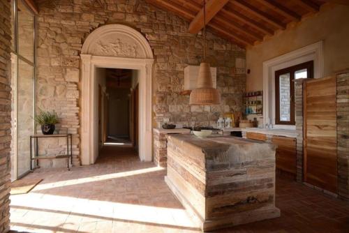 沃爾泰拉的住宿－Wohnung in Volterra mit Gemeinsamem Garten，一个带石墙和桌子的大厨房