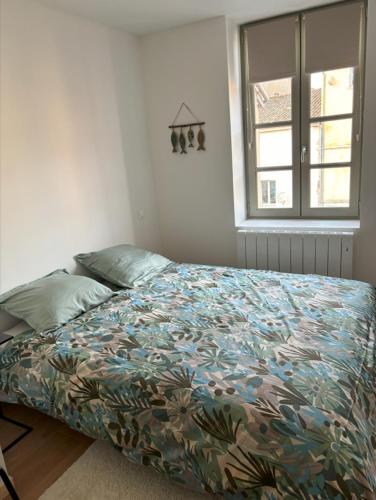 une chambre avec un lit avec une couette colorée et une fenêtre dans l'établissement La Maison d’Aromarie, à Tournus