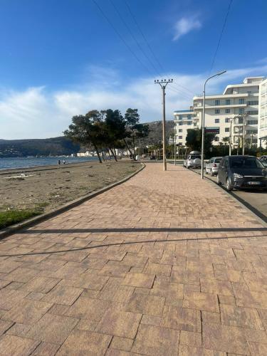 a brick sidewalk next to a beach with parked cars at Studio holidays in Shëngjin