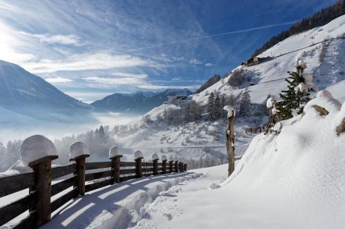 a fence covered in snow with a view of a valley at Enzianhof - Nature Apartments in San Giovanni in Val Aurina