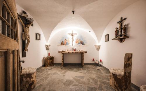 an altar in a church with a cross on the wall at Enzianhof - Nature Apartments in San Giovanni in Val Aurina