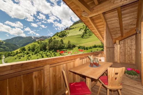 porche de madera con mesa y sillas de madera en Enzianhof - Nature Apartments, en San Giovanni in Val Aurina