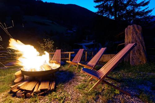 a fire pit with two chairs and a fire grill at Enzianhof - Nature Apartments in San Giovanni in Val Aurina