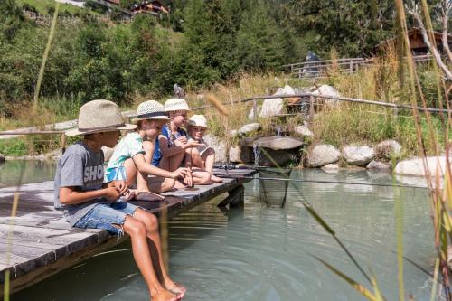 a group of children sitting on a dock in the water at Enzianhof - Nature Apartments in San Giovanni in Val Aurina