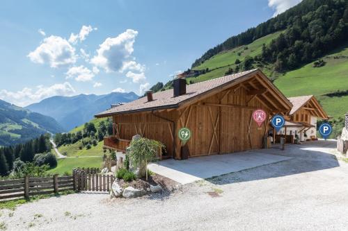 a large wooden building with mountains in the background at Enzianhof - Nature Apartments in San Giovanni in Val Aurina