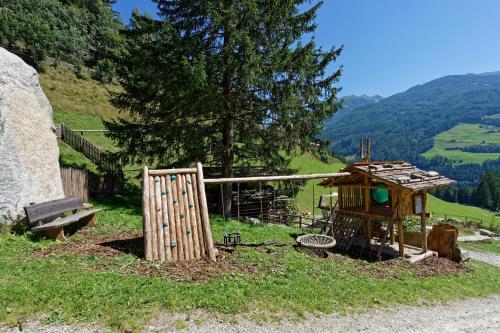 a small wooden house with a gate and a bench at Enzianhof - Nature Apartments in San Giovanni in Val Aurina