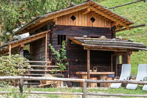 a log cabin with a table and chairs in front of it at Enzianhof - Nature Apartments in San Giovanni in Val Aurina