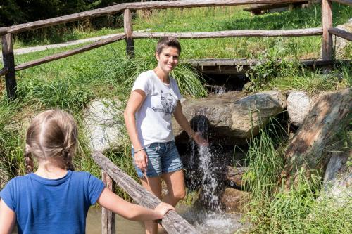 two girls are standing in a stream of water at Enzianhof - Nature Apartments in San Giovanni in Val Aurina
