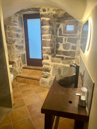 La salle de bains en pierre est pourvue d'une table et d'une fenêtre. dans l'établissement Gorgeous Stone House in the heart of Ardeche, à Montpezat-sous-Bauzon