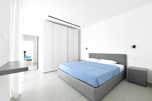 ein weißes Schlafzimmer mit einem blauen Bett und einem Schreibtisch in der Unterkunft Les Jolie Apartament in Lido di Jesolo