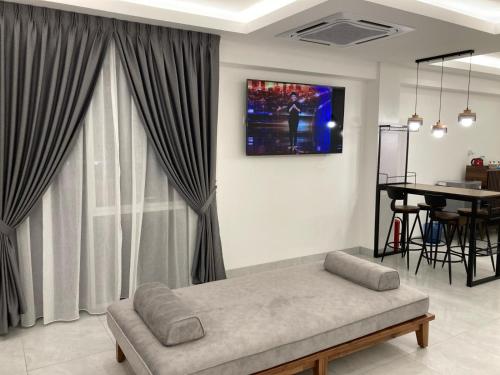 ein Wohnzimmer mit einem Sofa und einem TV an der Wand in der Unterkunft CS Junction Point - Family Deluxe Room FDR in Kuala Pilah