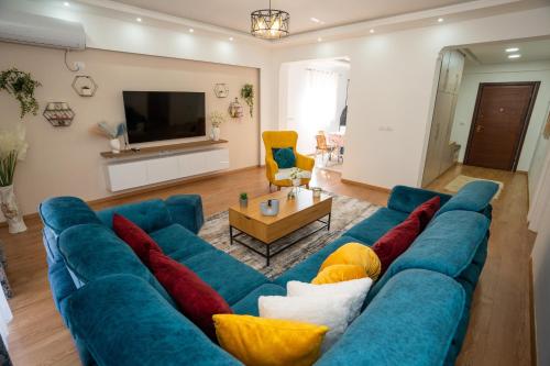 ein Wohnzimmer mit einer blauen Couch mit bunten Kissen in der Unterkunft Olivia Apartment in Sarandë